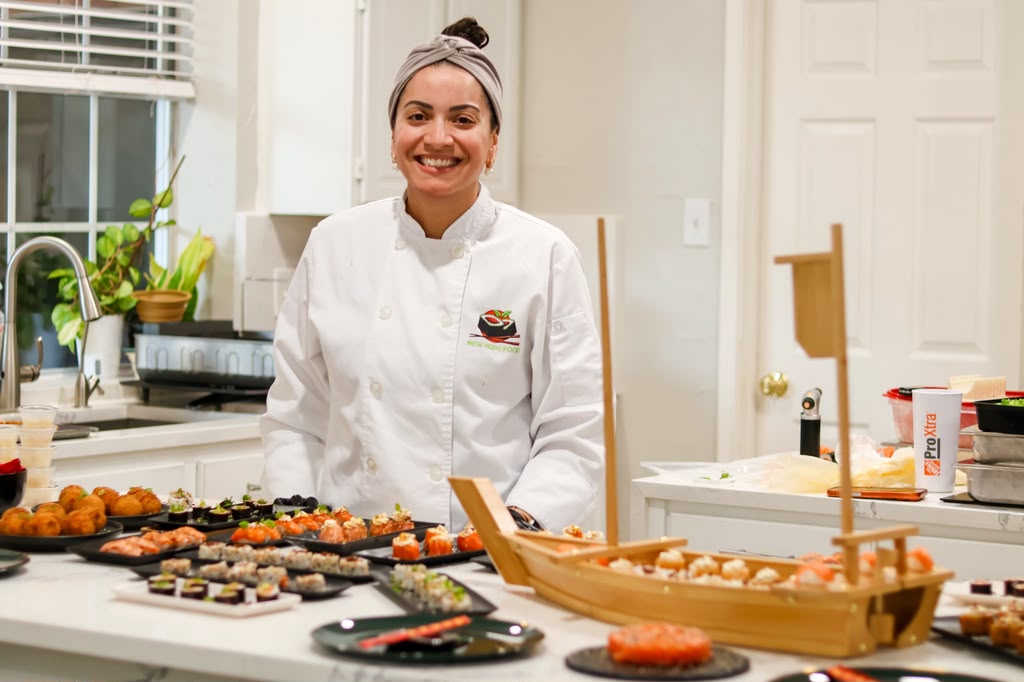 Chef Barbara smiling behind a table of sushi at a private event